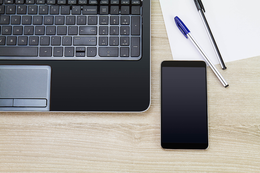 A mobile phone next to a computer, meant to show that you can text from computers