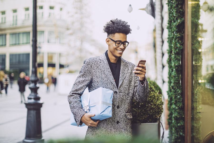 A holiday shopper holding a gift and texting