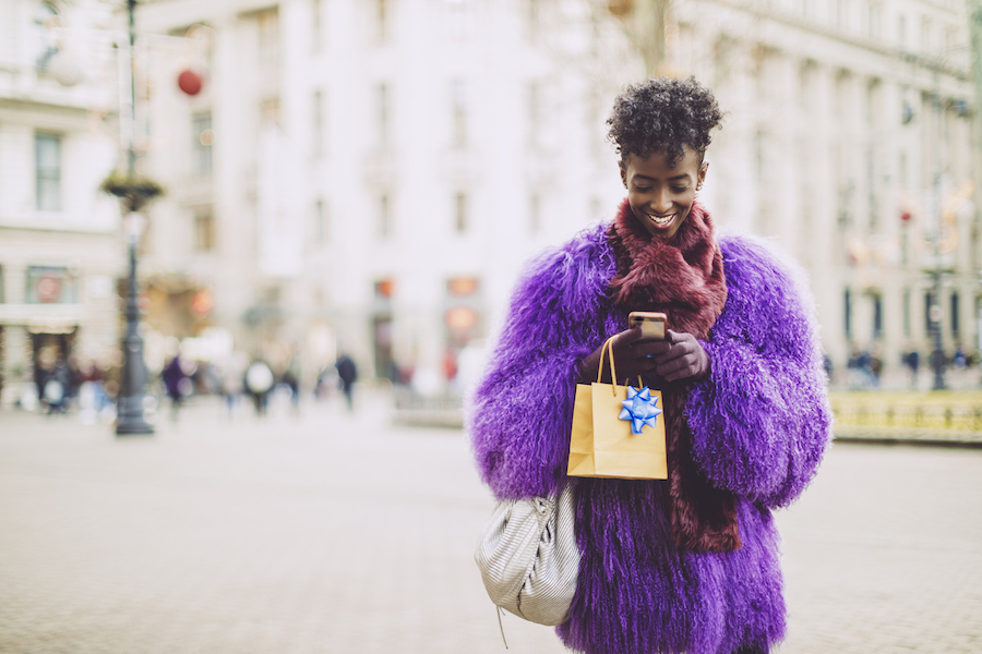 Woman texting and walking with shopping bags