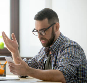 Man looking frustrated at his cell phone.