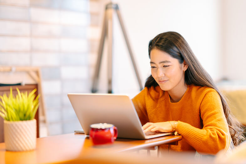 A young woman sending a text from her laptop using Microsoft Teams