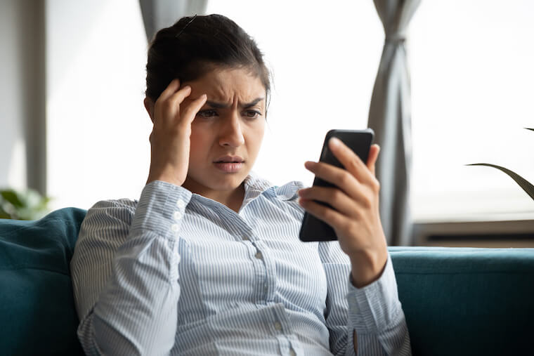 Woman looking frustrated at her mobile phone.