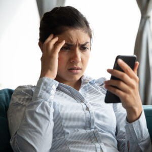 Woman looking frustrated at her mobile phone.