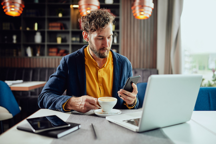 Man sitting by computer and sending a text message.
