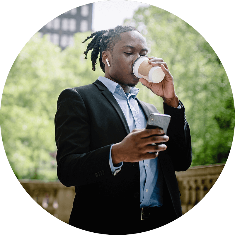Businessman drinking coffee at a park and using omnichannel messaging
