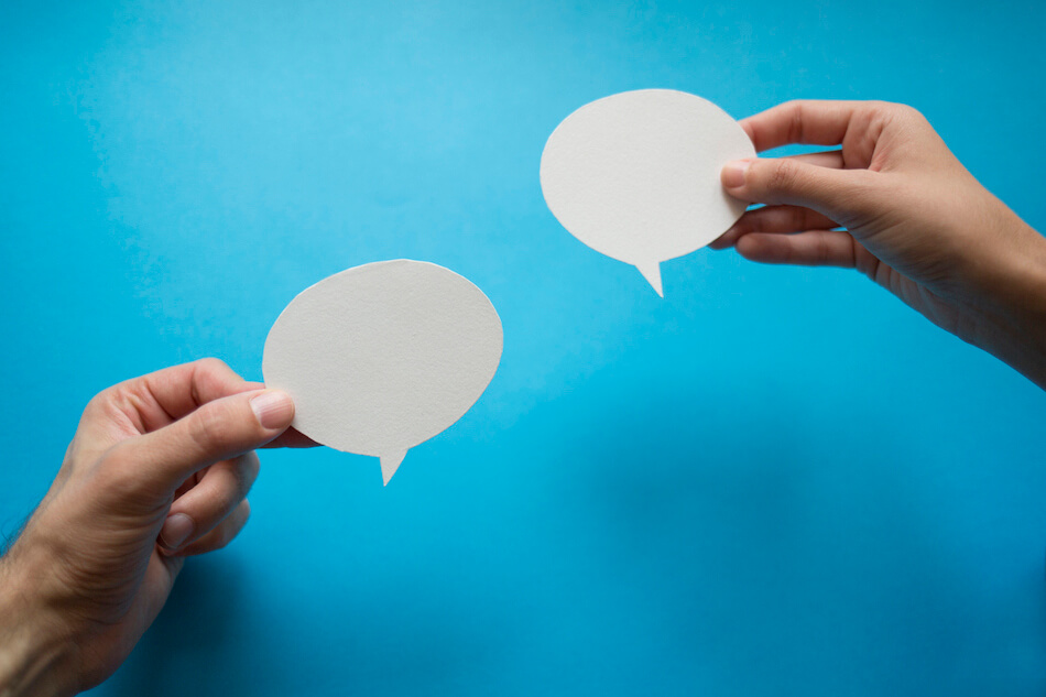 Hands holding paper chat bubbles