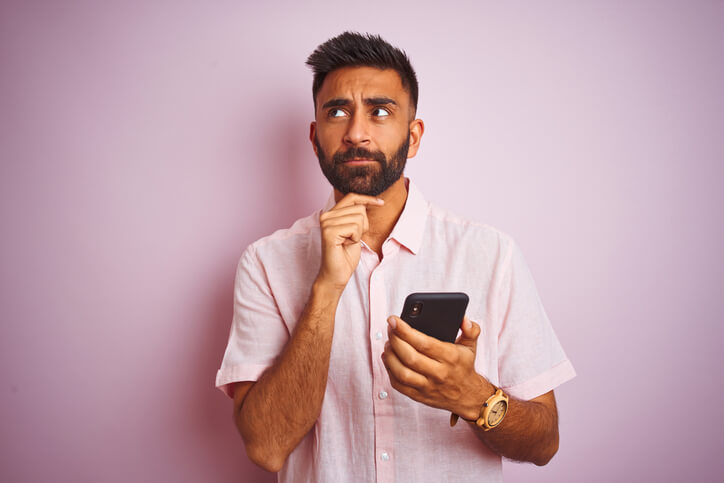 Man looking up from phone confused